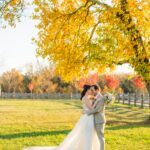 Here’s an intimate, and romantic picture of a couple in their wedding attire taken outdoors on a bright day, surrounded by lush trees and natural light.